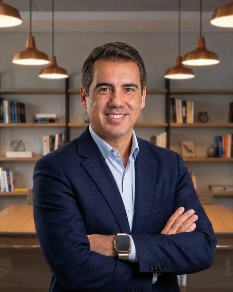 Roberto Calderon sorrindo, de camisa jeans, no coworking